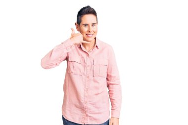 Kısa saçlı, günlük kıyafetler giyen, gülümseyen, el ve parmaklarıyla telefonla konuşan genç bir kadın. iletişim kavramları. 