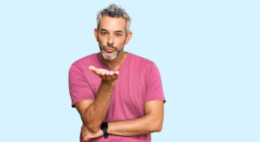 Orta yaşlı, gri saçlı, sıradan kıyafetler giyen, kameraya bakıp havada öpüşen, güzel ve seksi bir adam. aşk ifadesi. 