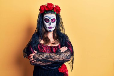 Sarı kuşkucu, gergin ve kollarını çapraz yapmış yüz ifadesini onaylamamak için ölü kostümü giymiş genç bir kadın. negatif kişi. 