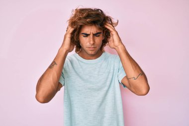 Stres yüzünden başı ağrıyan Latin kökenli genç bir adam günlük kıyafetler giyiyor. migren ağrısı. 
