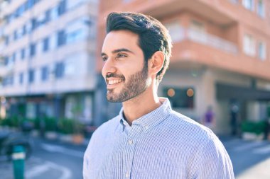 Genç İspanyol adam gülümseyerek şehirde mutlu bir şekilde yürüyor..