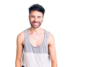 Yüzünde mutlu ve havalı bir gülümseme olan sıradan kıyafetler giyen genç İspanyol bir adam. şanslı kişi. 