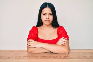 Genç, Asyalı, sıradan kıyafetler giyen, şüpheci ve gergin genç bir kız. Yüzünde çapraz kollarla onaylamayan bir ifade var. negatif kişi. 