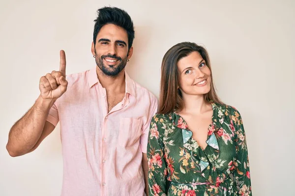 Güzel, genç bir çift sevgili bir numarayı gösterip işaret ederken kendinden emin ve mutlu bir şekilde gülümsüyor.. 