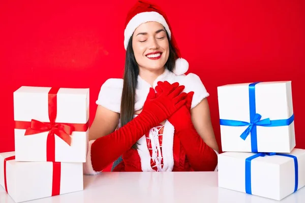 Молодая Женщина Костюме Санта Клауса Сидит Столом Подарками Улыбаясь Руками — стоковое фото