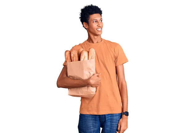 Νεαρός Αφροαμερικάνος Που Κρατάει Χάρτινη Σακούλα Ψωμί Κοιτάζοντας Αλλού Χαμόγελο — Φωτογραφία Αρχείου