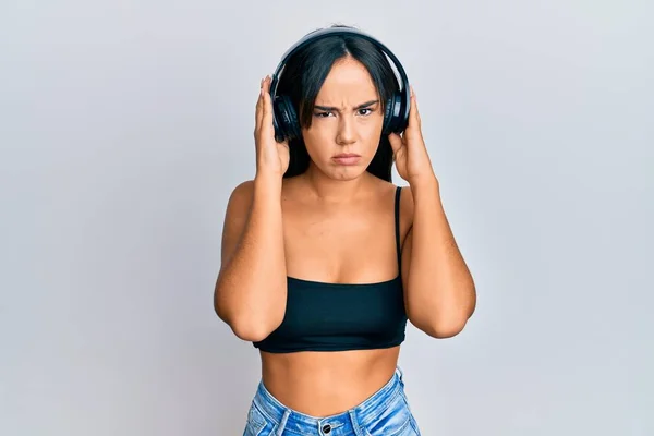 Junge Schöne Hispanische Mädchen Hören Musik Mit Kopfhörern Skeptisch Und — Stockfoto