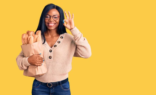 Νεαρή Αφροαμερικανή Γυναίκα Κρατώντας Χαρτοσακούλα Ψωμί Κάνει Υπογράψει Δάχτυλα Χαμογελώντας — Φωτογραφία Αρχείου