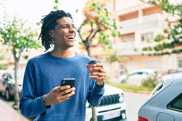 若いアフリカ系アメリカ人の男が街のスマートフォンを使って笑顔で — ストック写真