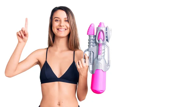 Young Beautiful Girl Wearing Bikini Holding Water Gun Surprised Idea — Stock Photo, Image