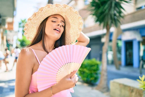 若いですヒスパニック女性オン休暇身に着けています夏スタイル使用手ファンで街の通り — ストック写真