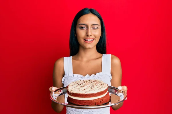 Joven Morena Sosteniendo Pastel Zanahoria Guiño Mirando Cámara Con Expresión — Foto de Stock