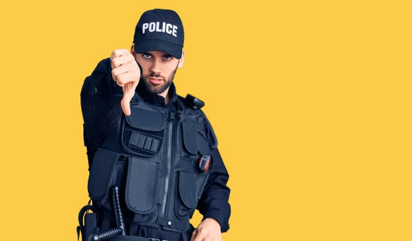 警官の制服を着た髭を生やした若いハンサムな男は不満そうに見え怒って拒絶を示し 親指を下にジェスチャーで否定する 悪い表現 — ストック写真