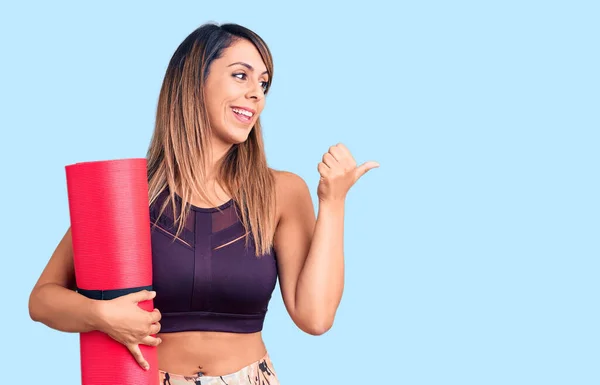 Young Beautiful Woman Wearing Sportswear Holding Yoga Mat Pointing Thumb — Stock Photo, Image