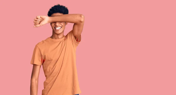 若いアフリカ系アメリカ人の男性は 陽気で面白い笑みを浮かべて腕で目を覆うカジュアルな服を着ている 視覚障害の概念 — ストック写真