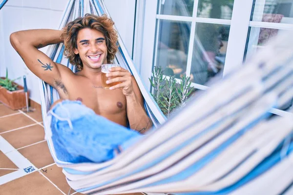 Genç İspanyol adam terasta hamakta uzanmış bira içerek rahatladı..