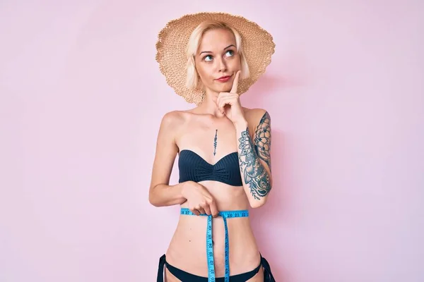 Młoda Blondynka Tatuażem Bikini Taśmą Mierzy Poważną Twarz Myśląc Pytaniu — Zdjęcie stockowe