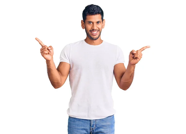 穿着休闲装的年轻拉丁男人带着自信的微笑 用手指指向不同的方向 复制广告空间 — 图库照片