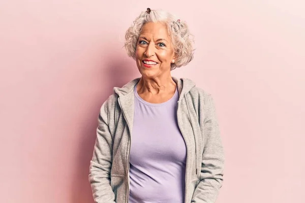 Senior grey-haired woman wearing casual sporty clothes looking positive and happy standing and smiling with a confident smile showing teeth