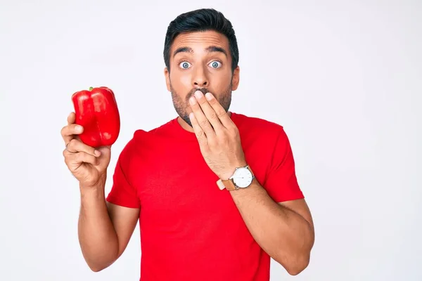 Young Hispanic Man Holding Red Pepper Covering Mouth Hand Shocked — Stock Photo, Image