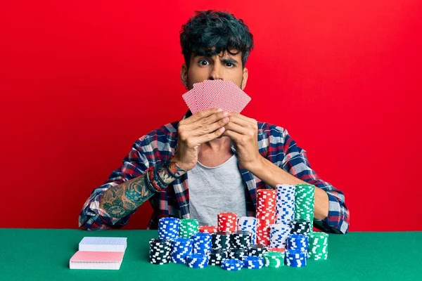 Jovem Hispânico Jogando Poker Cobrindo Rosto Com Cartas Face Choque — Fotografia de Stock