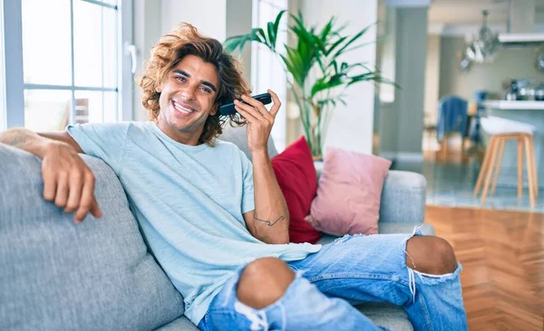 Joven Hombre Hispano Sonriendo Feliz Hablando Teléfono Inteligente Casa —  Fotos de Stock