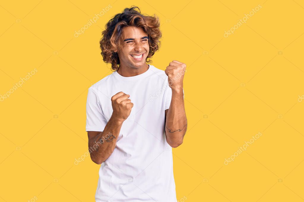 Young hispanic man wearing casual white tshirt celebrating surprised and amazed for success with arms raised and eyes closed. winner concept. 