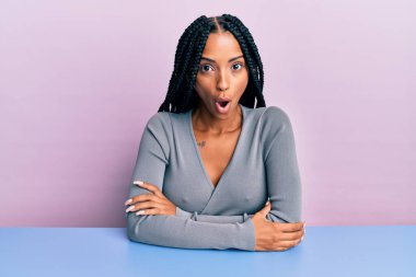 Güzel İspanyol kadın gündelik giysiler giymiş masada korkmuş ve şok olmuş bir şekilde oturuyor.. 