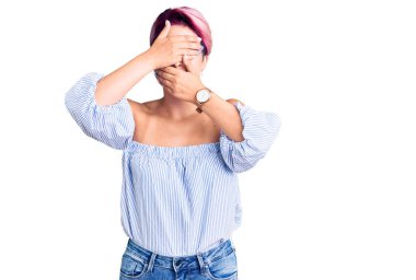 Pembe saçlı, sıradan kıyafetler giyen, gözleri ve ağzı elleri kapalı, şaşırmış ve şok olmuş genç bir kadın. duygu gizleme 