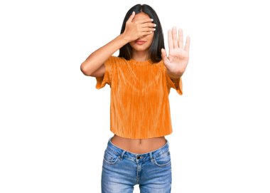 Genç esmer Arap kadın gündelik giysiler giyiyor, elleriyle gözleri örtüyor ve üzgün ve korku ifadeleriyle jestleri durduruyor. utangaç ve olumsuz kavram. 