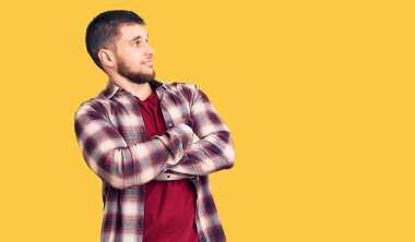 Sıradan gömlekler giyen genç, kolları çapraz ve kendinden emin bir şekilde yana bakan yakışıklı bir adam. 