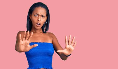 Yazlık kıyafetler giyen genç Afro-Amerikalı kadın avuç içi hareketlerini durduruyor, kızgın ve hayal kırıklığına uğramış ifade ediyor. 