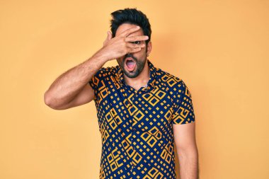 80 'lerin disko tarzı tişörtü giyen yakışıklı İspanyol bir adam. Şoka giriyor, yüzünü ve gözlerini kapıyor, utangaç bir ifadeyle parmaklarından bakıyor.. 