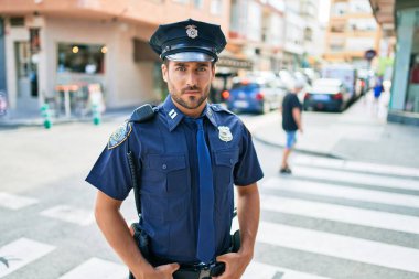 Polis üniforması giyen genç, yakışıklı İspanyol polis. Kasaba caddesinde ciddi bir ifadeyle dikiliyorsun..