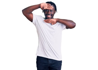 Young african american man with braids wearing casual white tshirt smiling cheerful playing peek a boo with hands showing face. surprised and exited  clipart