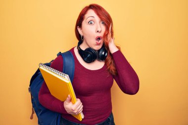 Sırt çantası ve kulaklık takan genç, güzel, kızıl saçlı bir bayan. Elinde not defteri var. Şaşırtıcı bir şekilde ağzı açık ve korkmuş.