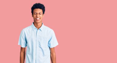 Genç, Afro-Amerikan bir adam günlük kıyafetler giyiyor. Dilini komik bir ifadeyle dışarı çıkarıyor. duygu kavramı. 