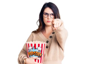 Güzel, genç, esmer bir kadın patlamış mısır yerken kamerayı işaret ediyor ve sen kendine güvenen, ciddi bir hareket yapıyorsun. 