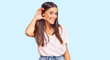 Günlük beyaz tişört giyen, ağzı kulaklarında gülümseyen genç İspanyol kadın dedikoduları ve dedikoduları dinliyor. Sağırlık kavramı. 