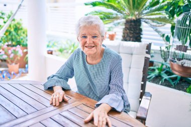 Evde mutlu gülümseyen gri saçlı yaşlı yaşlı kadın.