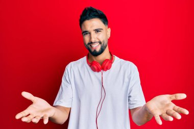 Sakallı genç adam kulaklık takarak müzik dinliyor. Gülümsüyor, yardım eli uzatıyor ve kabul ediyor.. 