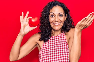 Orta yaşlı, kalbi olan güzel bir kadın başarıyı mutlu bir gülümsemeyle ve kazanan bir ifadeyle kutluyor elini kaldırarak. 