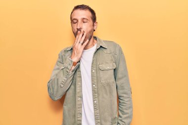 Gündelik kıyafetler giyen genç yakışıklı adam ağzıyla esnemekten sıkıldı. Huzursuz ve uykulu.. 