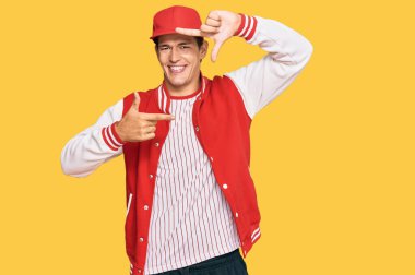 Beyzbol üniforması giyen yakışıklı beyaz adam gülümsüyor ve elleri ve parmakları gülen yüzlü bir çerçeve yapıyor. yaratıcılık ve fotoğrafçılık kavramı. 