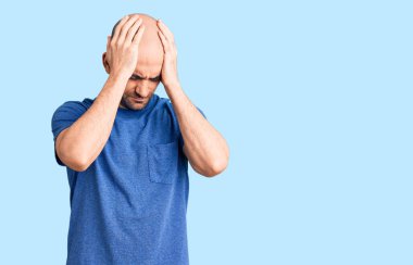 Genç yakışıklı bir adam günlük tişört giyiyor. Baş ağrısı, çaresiz ve stresli. Çünkü acı ve migren ağrısı var. Eller başının üstünde.. 