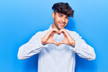 Gündelik kıyafetler giyen, aşık gülümseyen, elleriyle kalp sembolü yapan genç bir İspanyol. romantik kavram. 