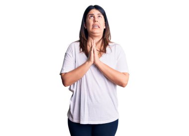 Genç, güzel, esmer bir kadın. Günlük tişört giyiyor. Elleriyle yalvarıyor ve dua ediyor. Yalvarıyor. 