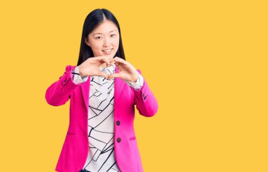 Zarif giysiler giyen genç, güzel Çinli bir kadın. Sevgiyle gülümseyen, kalp sembolü ve elleri olan bir kadın. romantik kavram. 