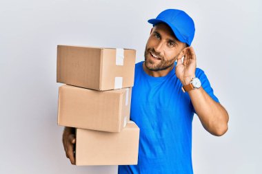 Sakallı, kurye üniforması giyen, teslimat paketleri taşıyan, ağzı kulaklarında dolaşan dedikoduları ve dedikoduları dinleyen yakışıklı bir adam. Sağırlık kavramı. 