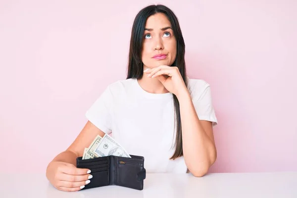 Młoda Kaukaska Kobieta Siedząca Przy Stole Trzymająca Portfel Banknotami Dolarowymi — Zdjęcie stockowe